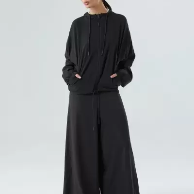 Mulher com conjunto preto de camisola com capuz e calças largas