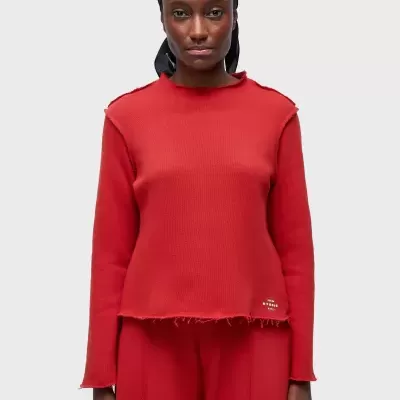 Blusa vermelha texturizada com logótipo MM6 na bainha, usada por modelo com lenço preto