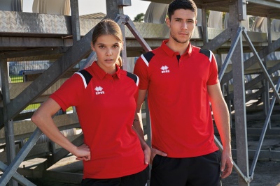 Homem e mulher com polo vermelho Errea em ambiente industrial