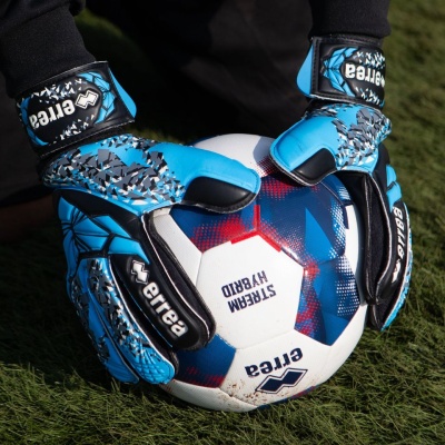 Luvas de guarda-redes azuis a segurar uma bola de futebol branca com azul e vermelho.