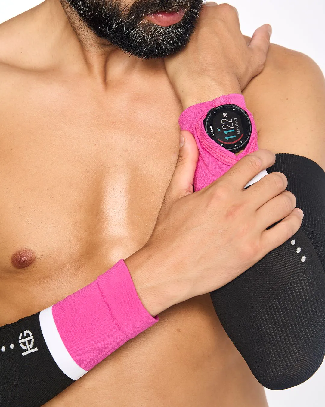 Smartwatch Garmin preto com suporte rosa no pulso esquerdo de alguém com mangas pretas e brancas.