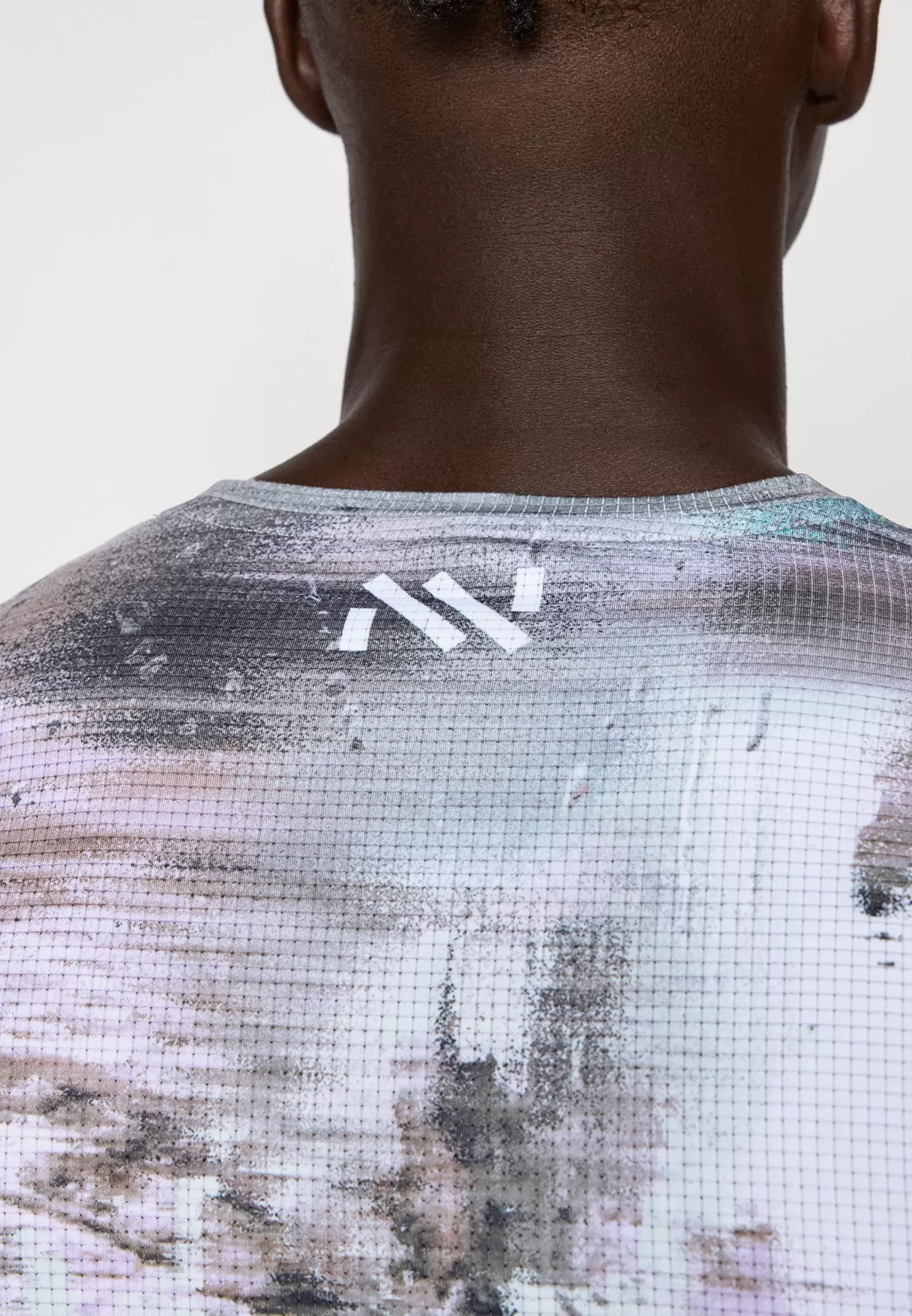 T-shirt desportiva cinza com padrão abstrato e logótipo branco nas costas