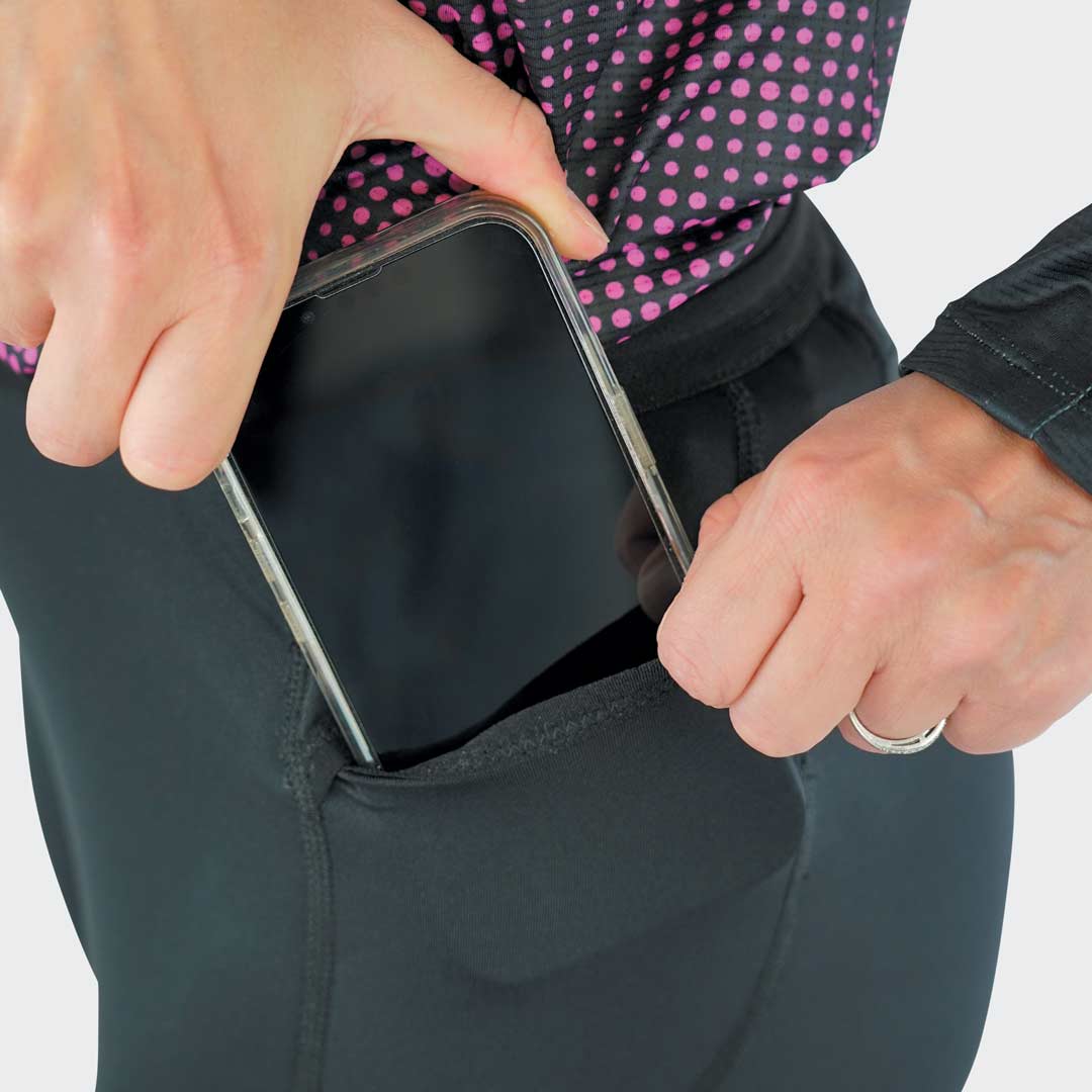 Pessoa a colocar um smartphone num bolso lateral de calças pretas.