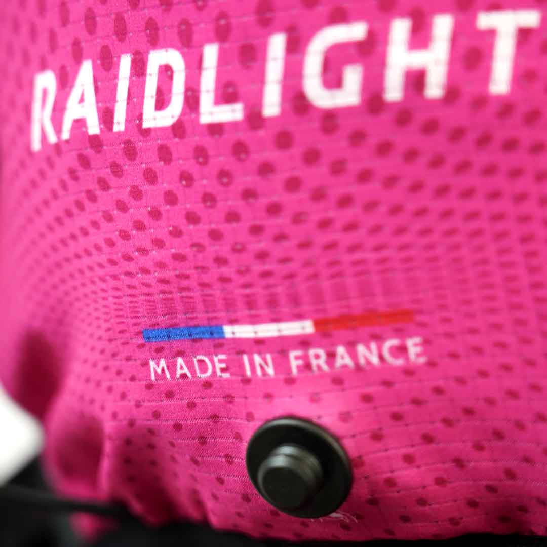 Detalhe de tecido cor de rosa com texto RAIDLIGHT e MADE IN FRANCE e botão preto
