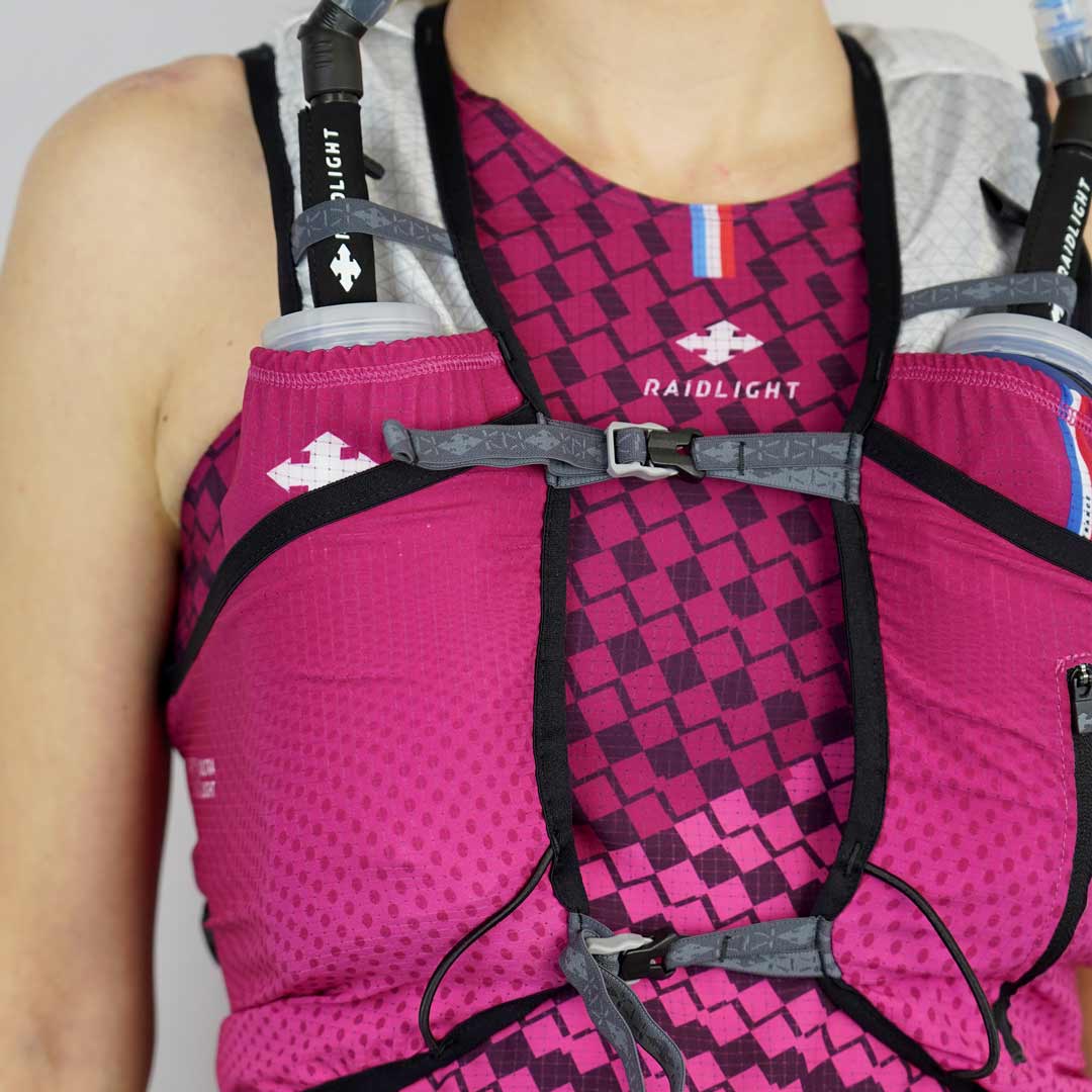 Colete desportivo rosa com reservatórios de água RAIDLIGHT, vestido sobre t-shirt rosa com padrão quadriculado