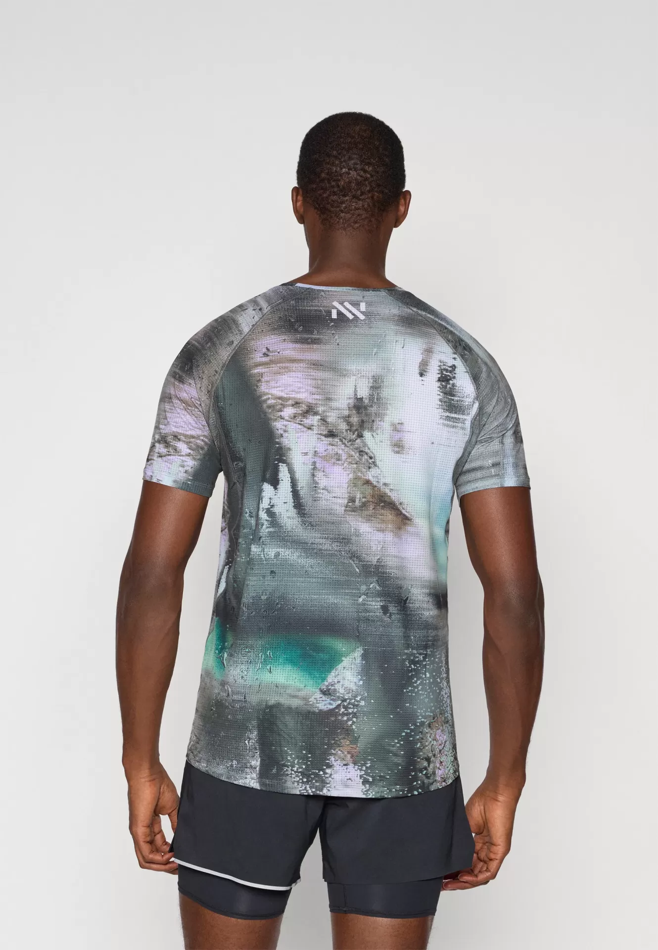 Homem visto de costas a usar camiseta desportiva colorida e calções pretos.