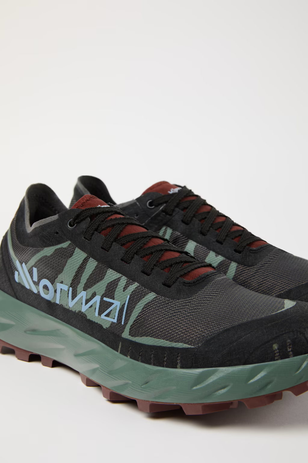 Sapatilhas de corrida trail pretas e verdes com sola salmão e texto HOKA na lateral.