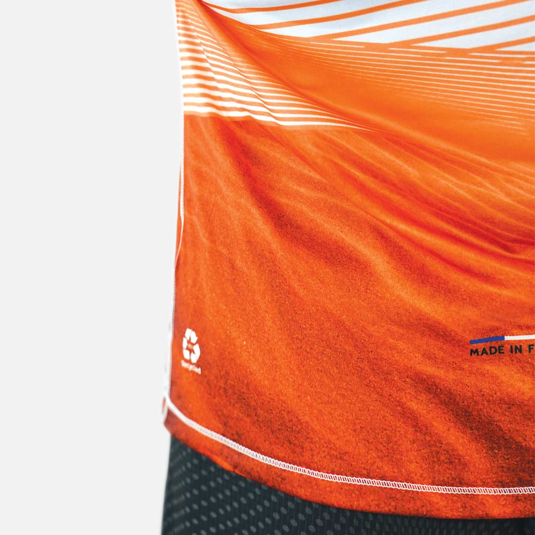 Detalhe de t-shirt desportiva laranja com linhas brancas e símbolos impressos