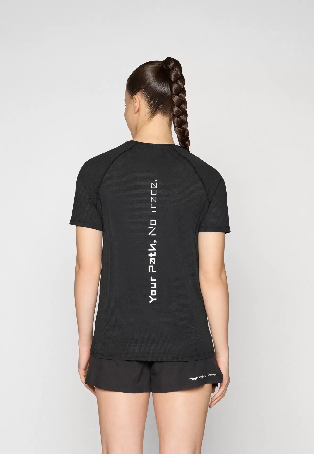 Pessoa de costas com t-shirt preta e calções pretos com texto branco vertical e pequeno