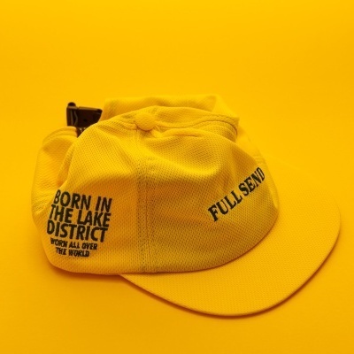 Boné amarelo com texto preto e fecho ajustável em fundo amarelo.