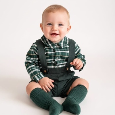 Bebé sorridente sentado com roupa verde e branca em fundo branco