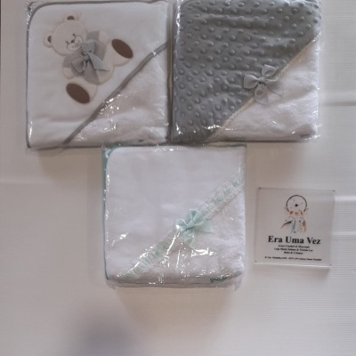 Três toalhas de bebé brancas com detalhes cinzentos e azul pastel, embaladas em plástico.