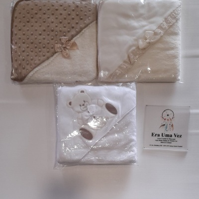 Três mantas para bebé embaladas em plástico, duas com laços e uma com ursinho, etiqueta Era Uma Vez ao lado