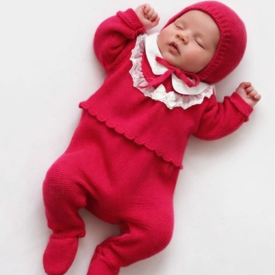 Bebé a dormir vestido com fato de malha vermelho e gola branca.