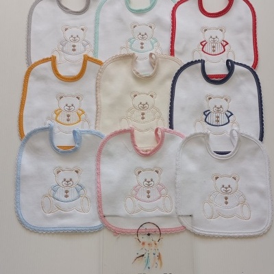 Babetes de bebé brancos com bordas coloridas e ursinho bordado, placa com texto ERA UMA VEZ