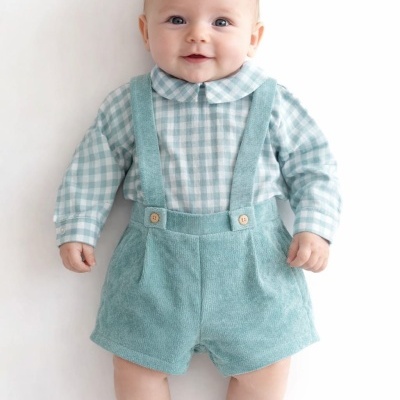 Bebé de roupa azul claro e branco a sorrir deitado sobre fundo branco