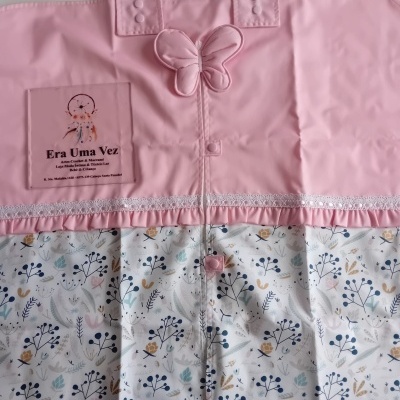 Produto têxtil rosa com borboleta e padrão floral, fechos de botão e texto 'opção 9' no fundo