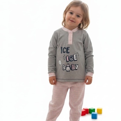 Criança com pijama cinzento e rosa com estampa e calças xadrez, em fundo branco com blocos coloridos no chão