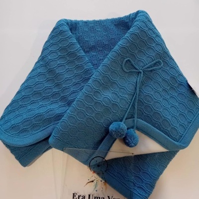 Cachecol ou manta azul texturizada com pompons e placa transparente com texto em português