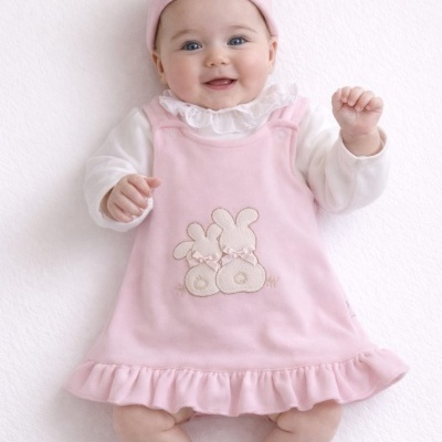 Bebé com vestido rosa e faixa na cabeça de cor rosa