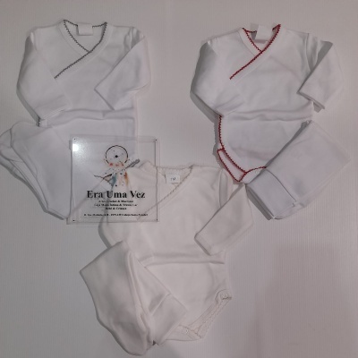 Conjunto de roupa de bebé branca com detalhes coloridos e placa da loja Era Uma Vez.