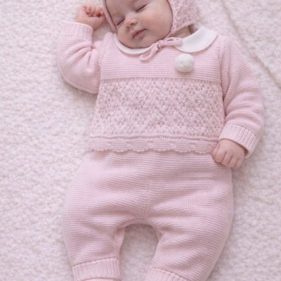 Bebé a dormir com roupa rosa de malha sobre manta bege claro