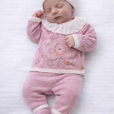 Bebé vestindo conjunto rosa de malha com gola branca rendada.