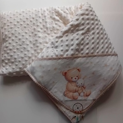 Manta de bebé branca com textura de bolinhas e ilustração de urso e coelho num canto