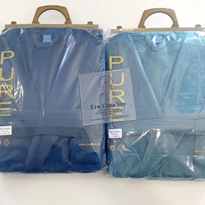 Dois robes de homem azuis embalados em plástico com alças e etiquetas visíveis.