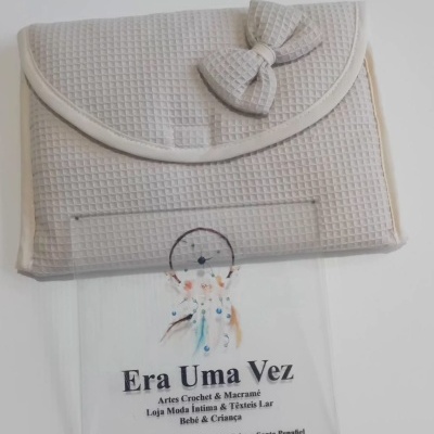 Bolsa branca com textura xadrez e laço decorativo sobre placa transparente com texto em português.