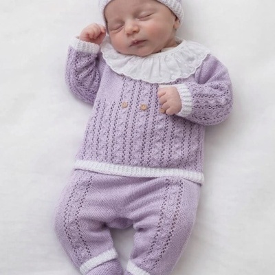 Bebé vestido com conjunto de malha lavanda e branco deitado
