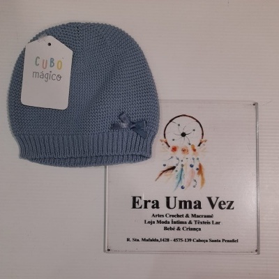 Gorro azul de malha com laço e etiqueta e placa informativa da loja Era Uma Vez.