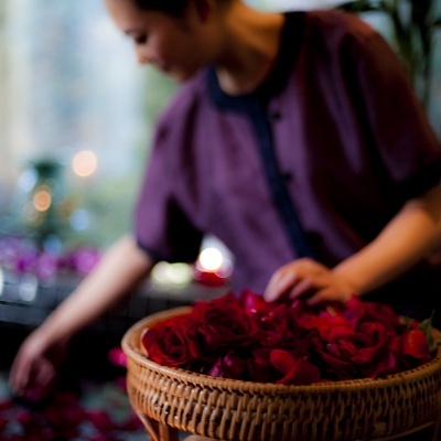 Cesto de vime com rosas vermelhas e pessoa a organizar flores