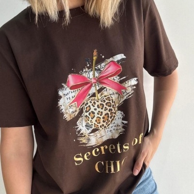 T-shirt castanha com estampa de maçã padrão oncinha e texto 'Secrets of CHIC'