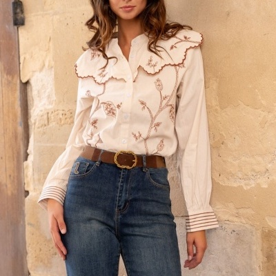 Blusa feminina branca com bordados florais e jeans azuis com cinto