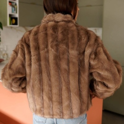 Casaco de pelo sintético castanho com riscas verticais e calças de ganga azuis