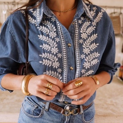 Camisa de ganga azul bordada com flores brancas, jeans e acessórios dourados