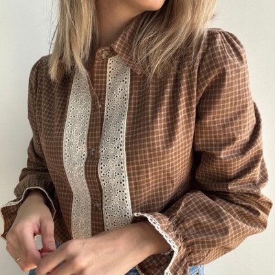 Blusa castanha xadrez com renda branca e calças jeans azuis