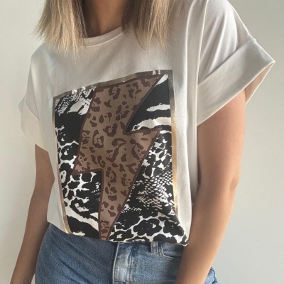 T-shirt branca com estampa de raio em padrão animal print e calças de ganga azuis