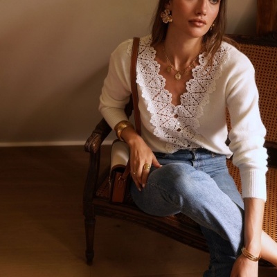 Mulher com camisola branca e calças de ganga sentada numa cadeira de madeira com palhinha