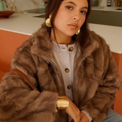 Mulher com casaco de pele sintética castanho e acessórios dourados grandes