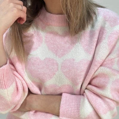 Camisola rosa com corações brancos e rosa e gola canelada, usada com jeans azuis.