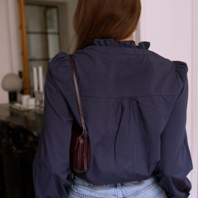 Blusa azul escura de mangas longas com gola franzida vista de costas