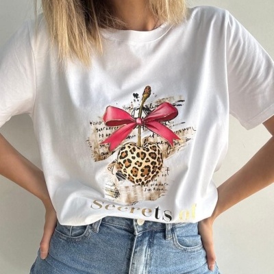 T-shirt branca com estampa de maçã e laço cor-de-rosa, vestida com jeans azuis