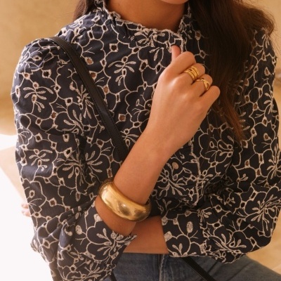 Blusa preta com padrão branco de folhagem e acessórios dourados