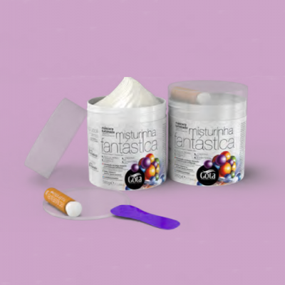 Frascos de creme branco com rótulo misturinha fantástica da marca Gota, tubo laranja e espátula roxa em fundo lilás