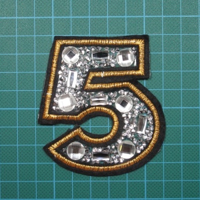 Emblema numero 5 base de Cola com pedras, e Rebordo Bordado em Lurex sobre Feltro.8cm x 7cm