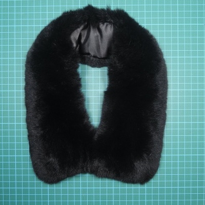 Gola de pêlo preta com forro preto sobre superfície verde quadriculada