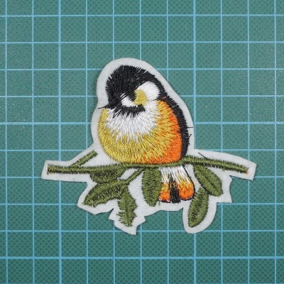 Patch bordado de pássaro colorido sobre um fundo quadriculado azul.