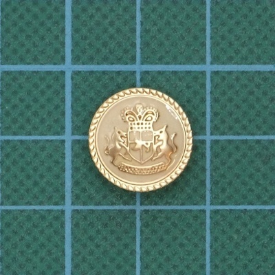 Botão dourado com brasão em fundo verde quadriculado